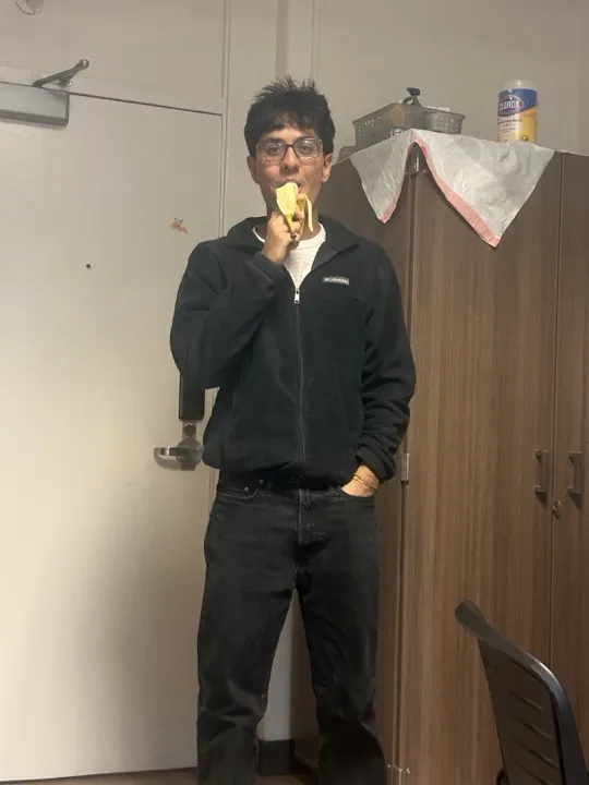 Arpit eating a banana in a dorm room