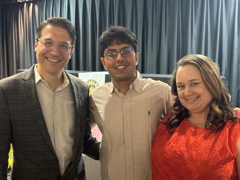 Arpit with two people in front of a stage