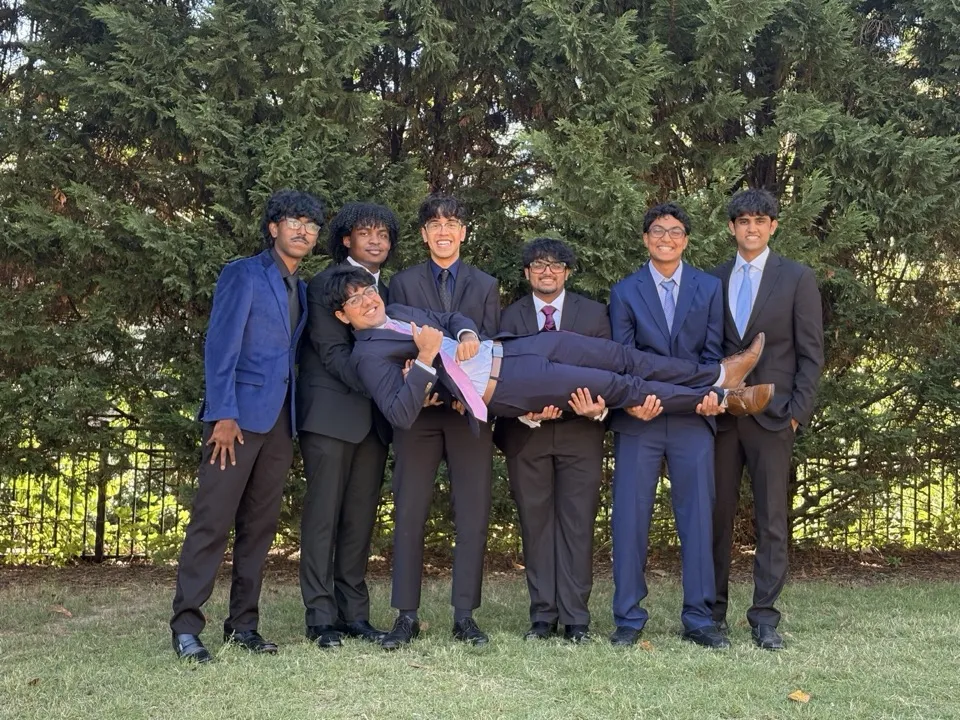 Friends in suits holding one of the group sideways